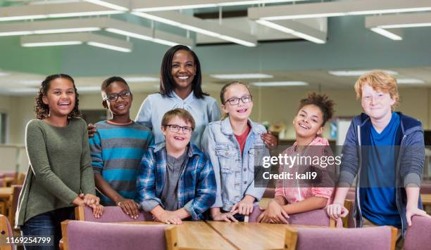 garçon avec le syndrome de vers le bas, professeur, camarades de classe dans la bibliothèque - down syndrome child african american photos et images de collection