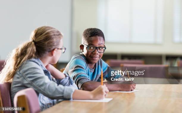twee multi-etnische basisschool studenten schrijven - two kids looking at each other stockfoto's en -beelden