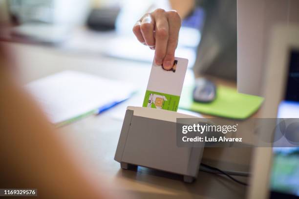 female receptionist inserting a medical card in machine - krankenversicherung stock-fotos und bilder