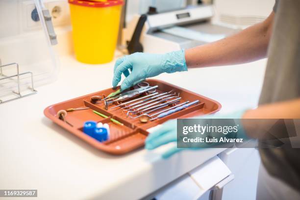 woman arranging dental tools in a tray at clinic - arzthelferin stock-fotos und bilder