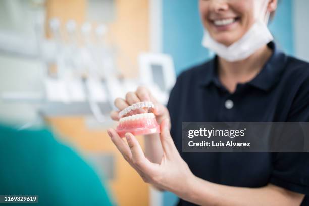 orthodontist explaining an implant to a patient in clinic - dentadura postiza fotografías e imágenes de stock