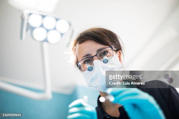 dentist treating patient in medical clinic - dental stock-fotos und bilder