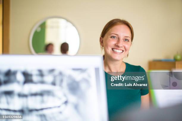 smiling woman at dental clinic reception desk - dental office front stock pictures, royalty-free photos & images