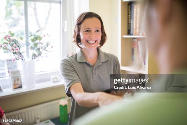 receptionist greets patient with a friendly handshake - gray polo shirt stock pictures, royalty-free photos & images