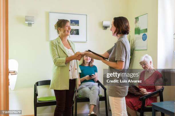 hospital staff greeting female patient in waiting area - lounge chair foto e immagini stock