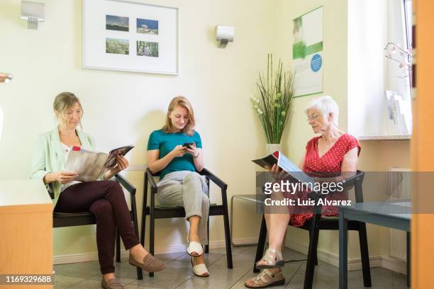 women in a clinic waiting room - überkreuzte beine stock-fotos und bilder
