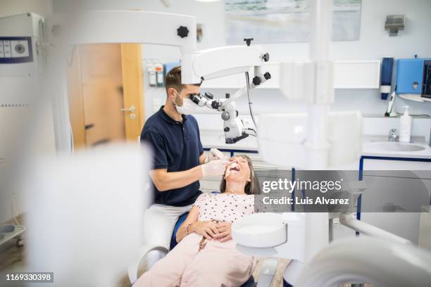 dentist examining senior female patient teeth - tandarts stockfoto's en -beelden