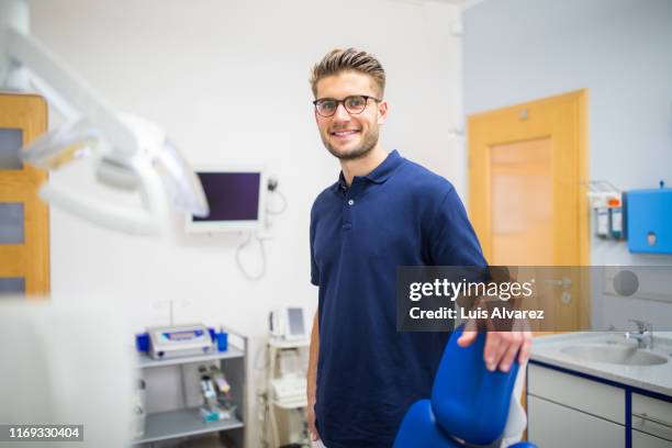 portrait of a dental expert in his clinic - navy blue polo shirt stock pictures, royalty-free photos & images