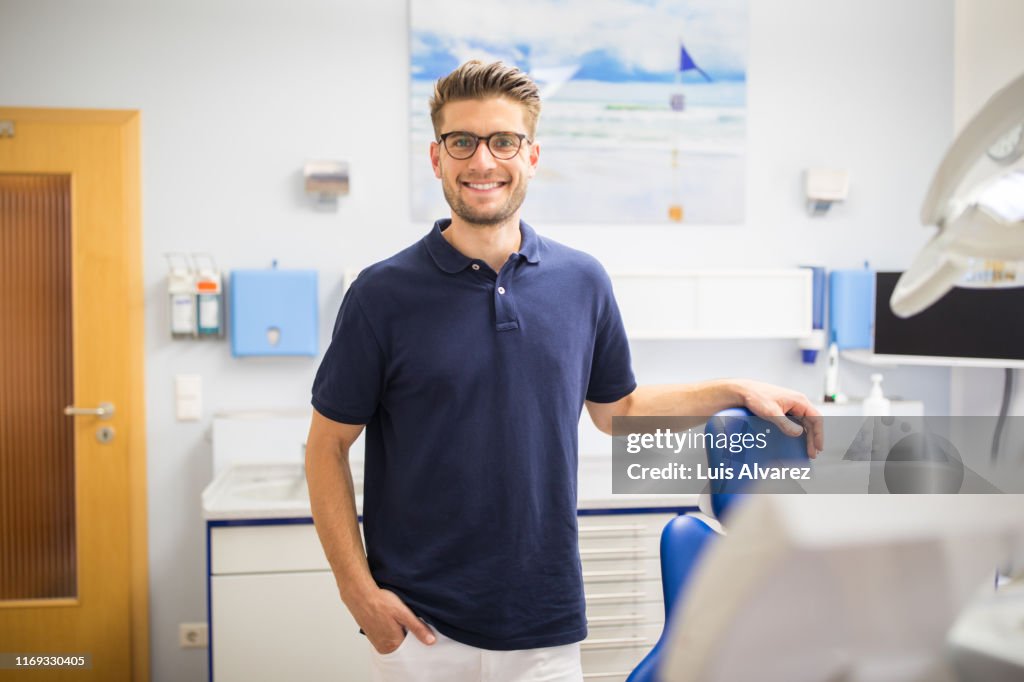 Confident male dentist standing in his clinic