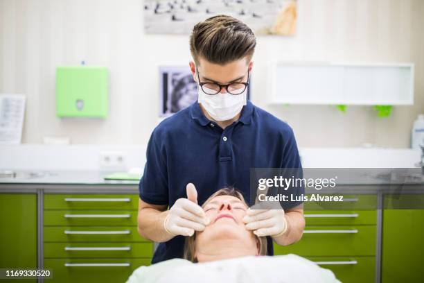 orthodontist examining mature woman - navy blue polo shirt stock pictures, royalty-free photos & images