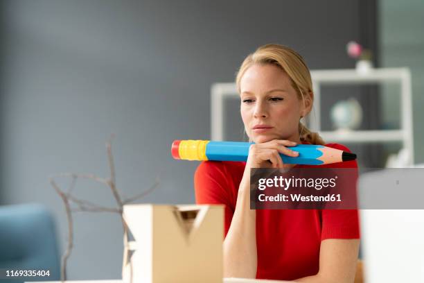 young woman in office with oversized pen and architectural model on desk - pen mockup stock-fotos und bilder