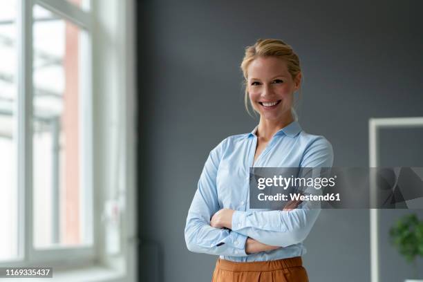 portrait of smiling young businesswoman in office - bluse stock-fotos und bilder