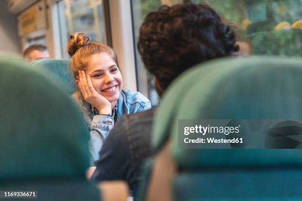 portrait of happy young woman travelling by train with her boyfriend, london, uk - flirting stockfoto's en -beelden