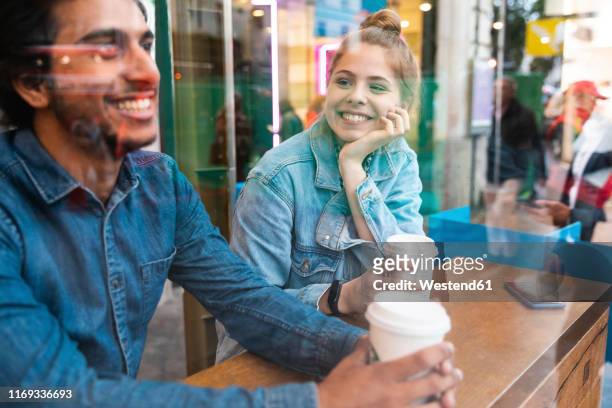 portrait of smiling young woman in a coffee shop looking at young man - versierd jak stockfoto's en -beelden