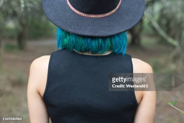 back view of young woman with dyed blue and green hair wearing black hat - camisa sin mangas fotografías e imágenes de stock