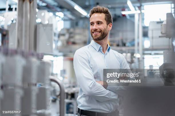 portrait of a confident businessman in a modern factory - mirar alrededor fotografías e imágenes de stock