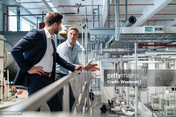 two businessmen talking in a modern factory - herstellendes gewerbe stock-fotos und bilder