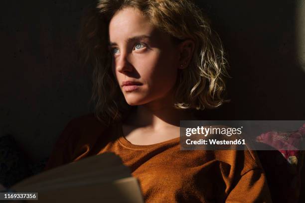 portrait of pensive student with book looking at distance - aufschauen stock-fotos und bilder