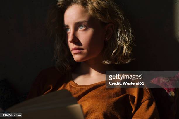 portrait of pensive student with book looking at distance - alto contraste imagens e fotografias de stock