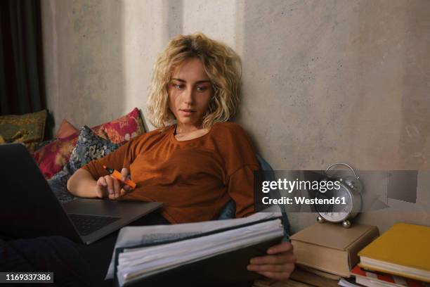 portrait of blond student on bed working on laptop - frau uhr stock-fotos und bilder