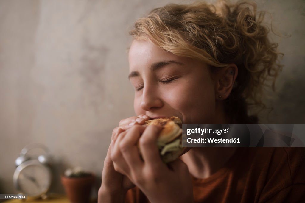 Portrait of young woman eating Hamburger