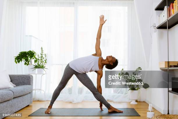 woman practicing yoga at home - salle yoga photos et images de collection