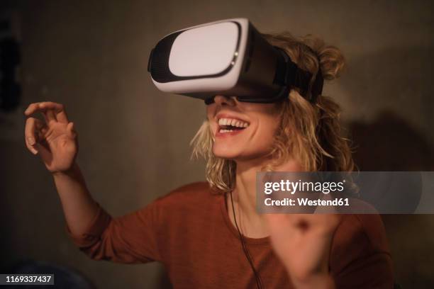 laughing young woman using virtual reality glasses at home - virtual reality glasses stockfoto's en -beelden