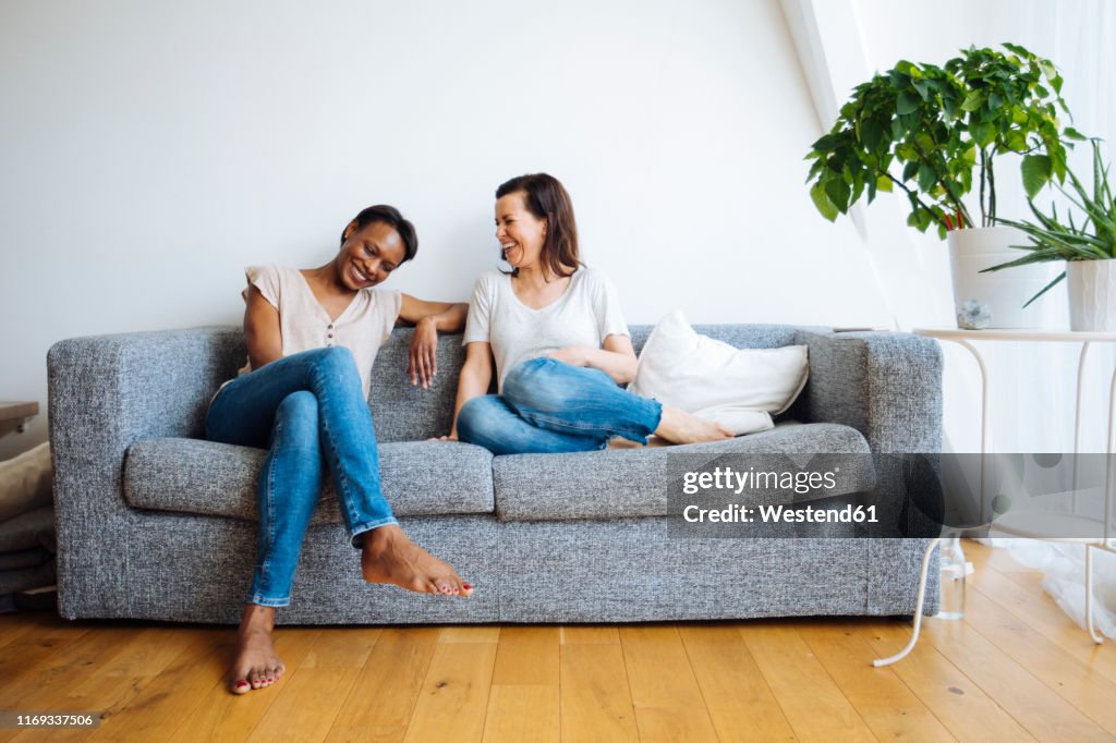 Two happy relaxed women sitting on couch at home