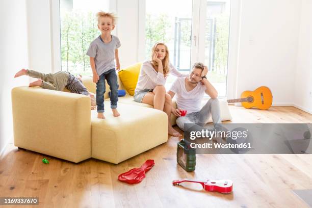 parents in living room of their new home watching boys romping about - toddler musical instrument stock pictures, royalty-free photos & images