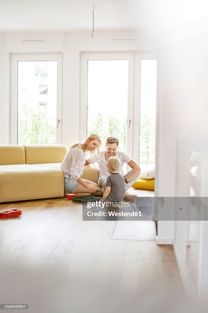 Happy family with a son playing in living room of their new home