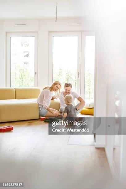 happy family with a son playing in living room of their new home - living room young couple stock-fotos und bilder