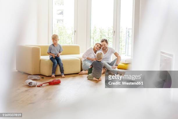 happy family with two sons playing in living room of their new home - new sofa stock pictures, royalty-free photos & images