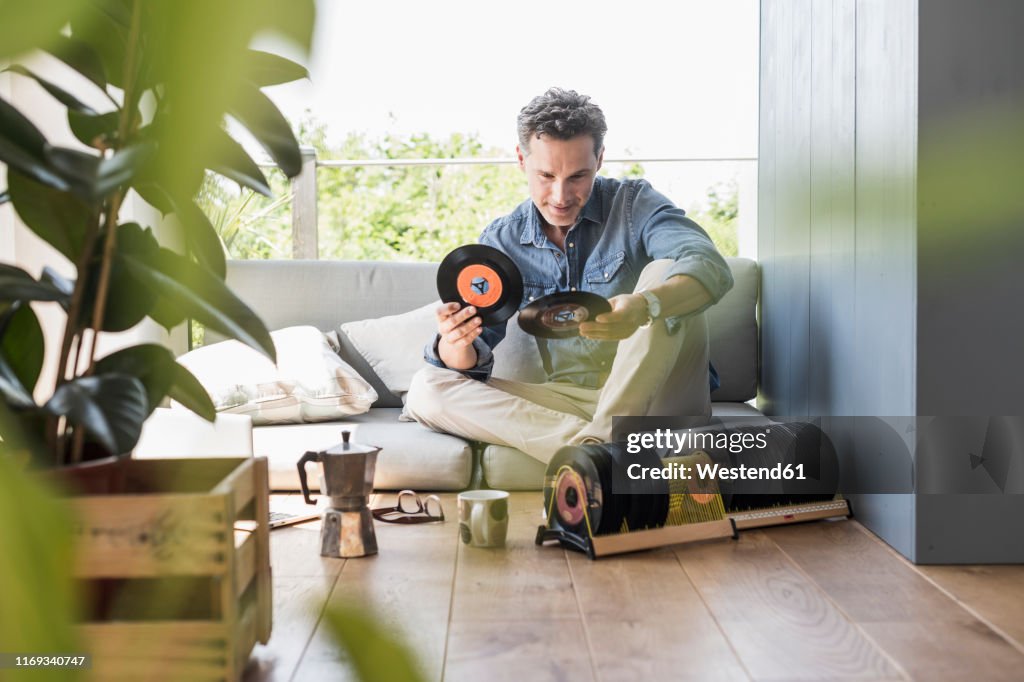 Mature man sitting at home, looking at vintage sigle recors
