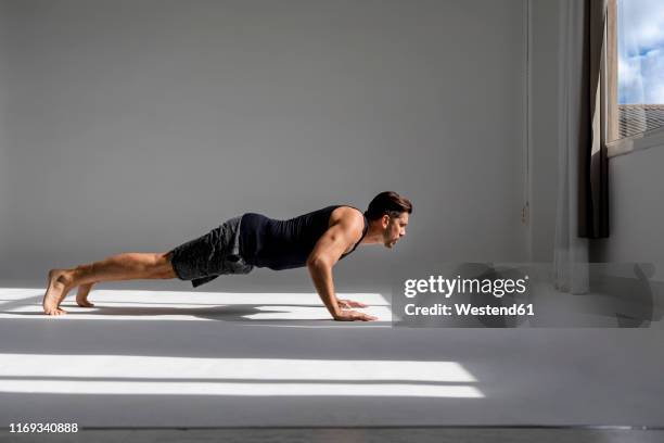 athlete worming up in sunlit studio - push ups stock-fotos und bilder