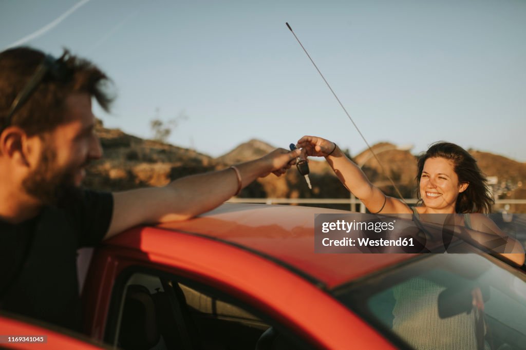 Couple exchanging car keys on a road trip