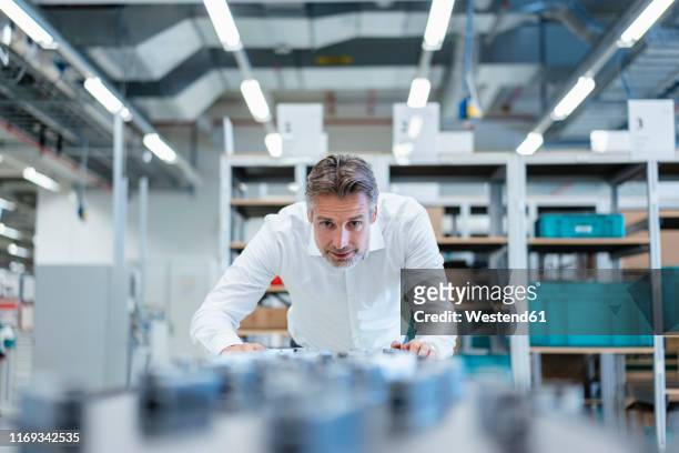 businessman in a modern factory hall examiming workpieces - drehmaschine stock-fotos und bilder