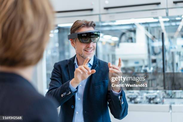 businessman with ar glasses and businesswoman in a modern factory - body language at work stock-fotos und bilder