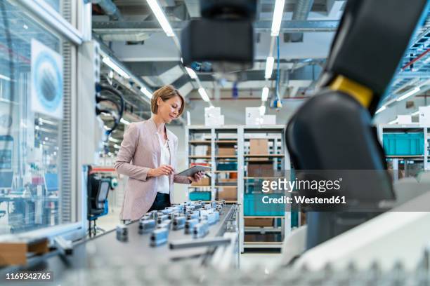 businesswoman with tablet in a modern factory hall - automation industrie stock-fotos und bilder
