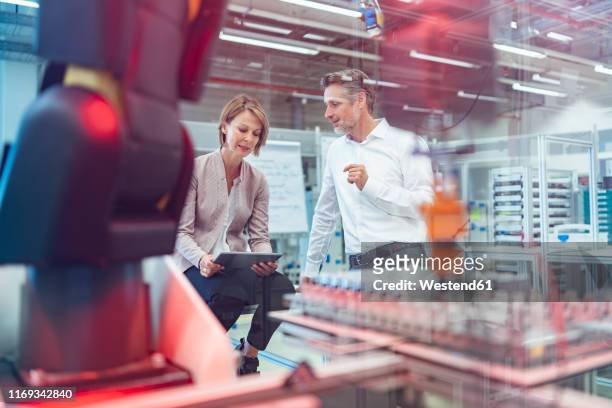 businessman and businesswoman talking in a modern factory hall - entrepreneur manufacturing stock pictures, royalty-free photos & images