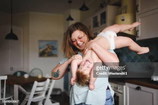 portrait of mother playing with her little son in the kitchen - tickling stock-fotos und bilder