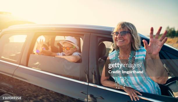 senior woman and her grandchildren are waving from the car - family waving stock pictures, royalty-free photos & images