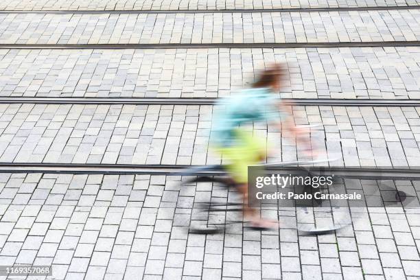 city biker in motion between railroad track - straßenbahnstrecke stock-fotos und bilder