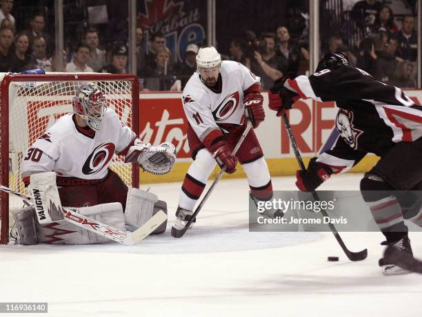 Cam Ward of the Carolina Hurricanes prepares to make a save while teammate Justin Williams waits for the rebound off of Sabres' Jason Pominville...