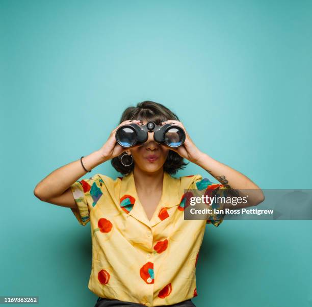cute young woman using binoculars - verrekijker stockfoto's en -beelden