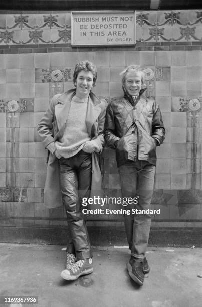 English rock guitarist, singer, actor and radio DJ Steve Jones and English drummer Paul Cook of punk rock band The Sex Pistols standing under a sign...