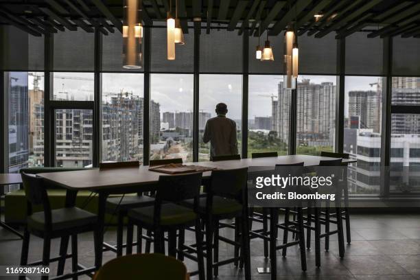 An employee standing at the window looks out over construction sites from the Amazon.com Inc. Office campus in Hyderabad , India, on Friday, Sept. 6,...
