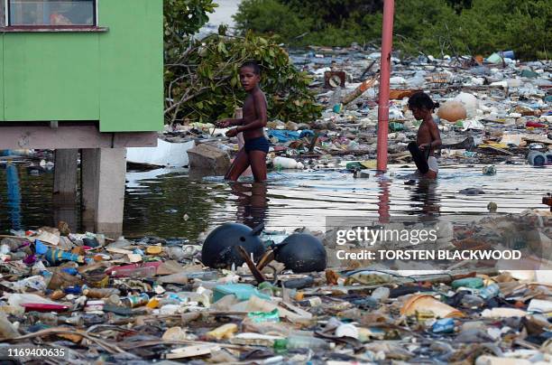 Children wade through floating garbage to reach their house as king tides inundate Funafuti Atoll, 19 February 2004, home to nearly half of Tuvalu's...