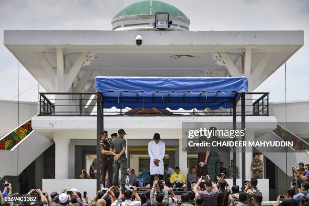 Man is whipped in public by a member of the Sharia police in Banda Aceh on September 19, 2019. - A trio of canoodling couples were publicly flogged...