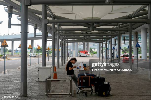 Woman waits for a taxi outside Indira Gandhi International airport in New Delhi on September 19 as road transport services have called for a one-day...