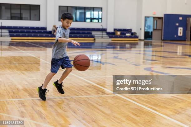 joven practica regate de baloncesto en el gimnasio de la escuela - dribbling sport fotografías e imágenes de stock
